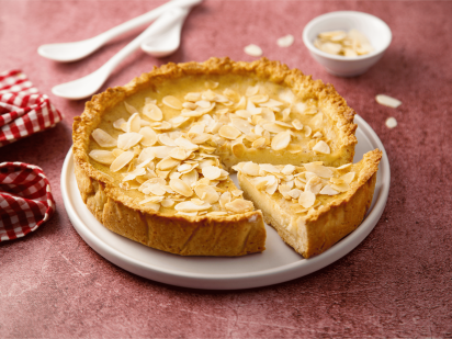 Mandel Tarte mit Schärdinger Cremig auf einem Teller auf einem roten Tischtuch